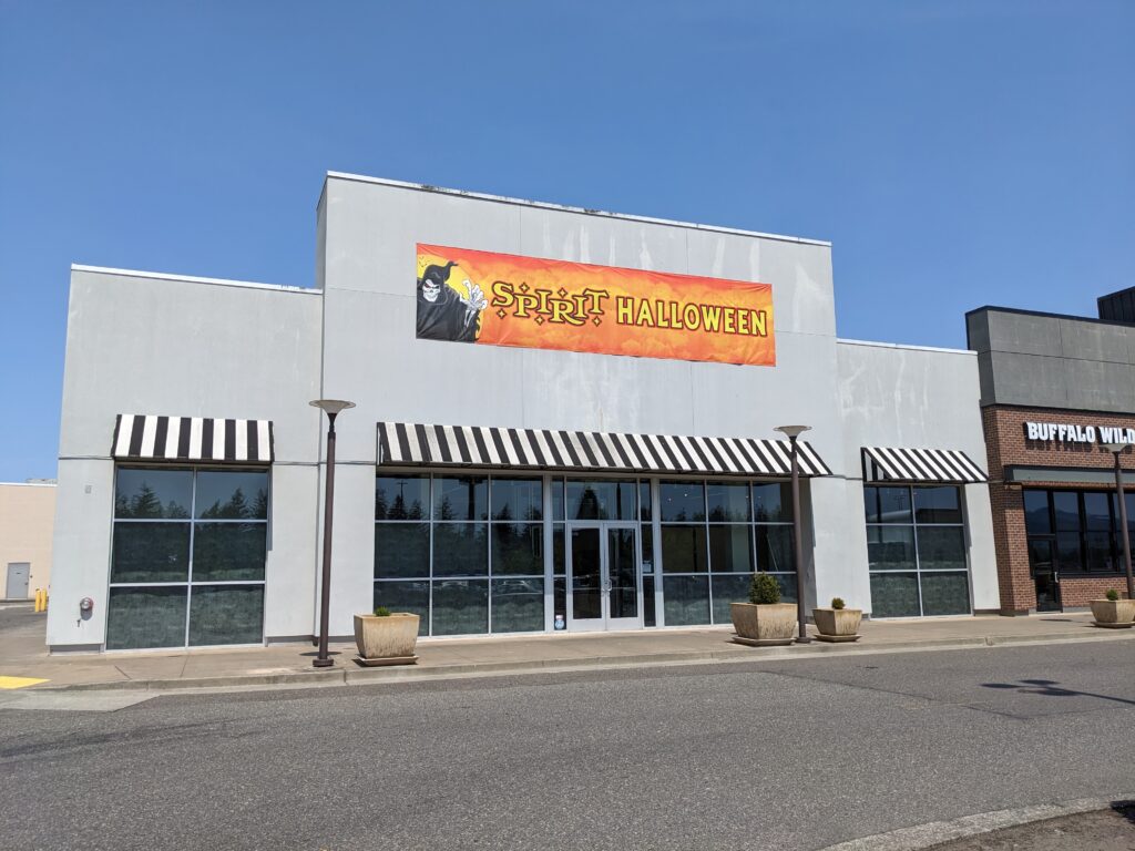 Spirit Halloween's seasonal gray storefront has a large orange banner over the awnings.