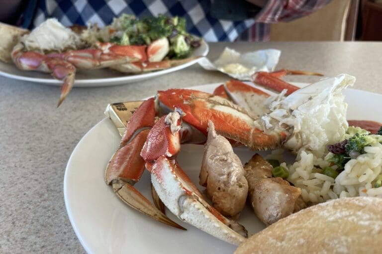 Crab served with potatoes and vegetables on a white plate.