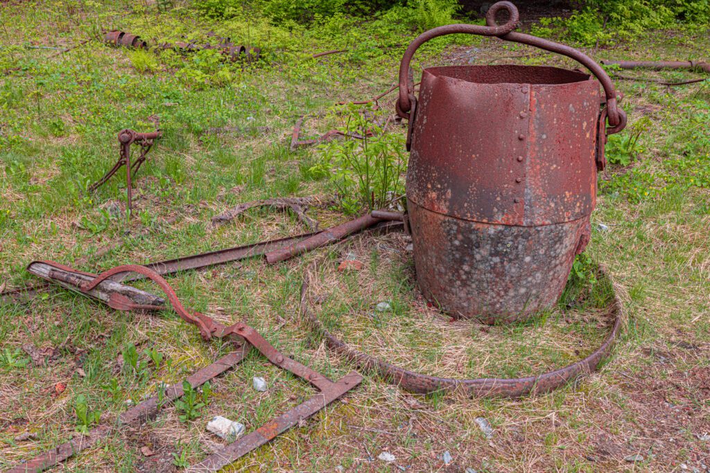 Rusty old gear are left on the grass for visitors to look at.