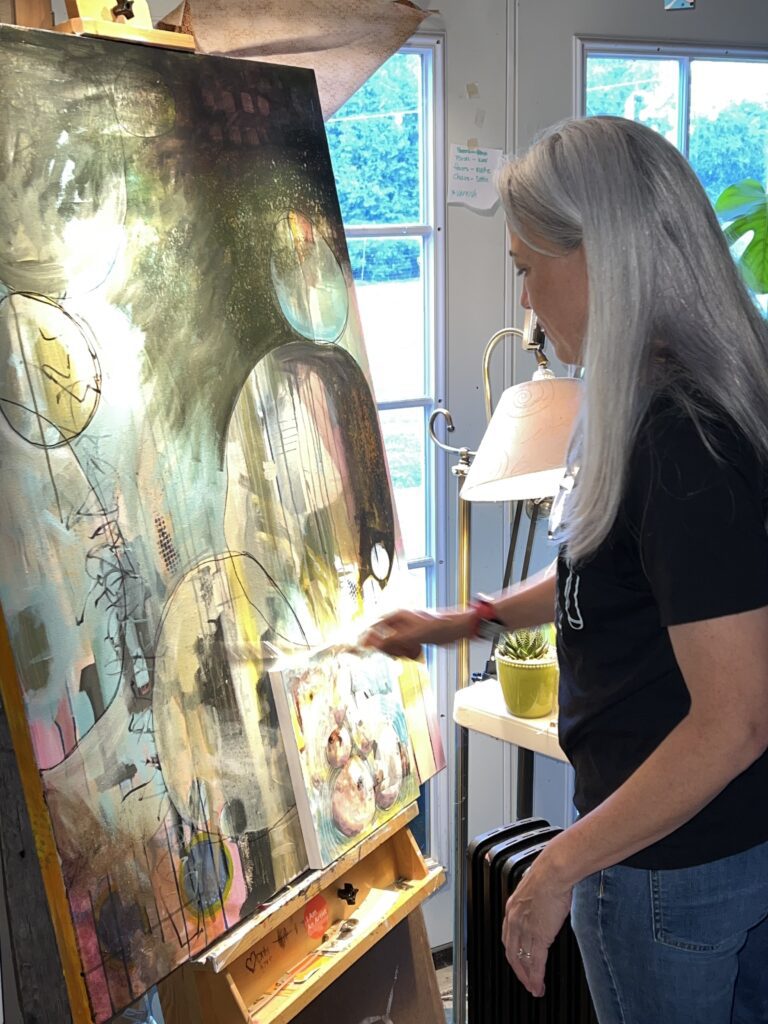 Mary Quintrall paints on a canvas at her home.