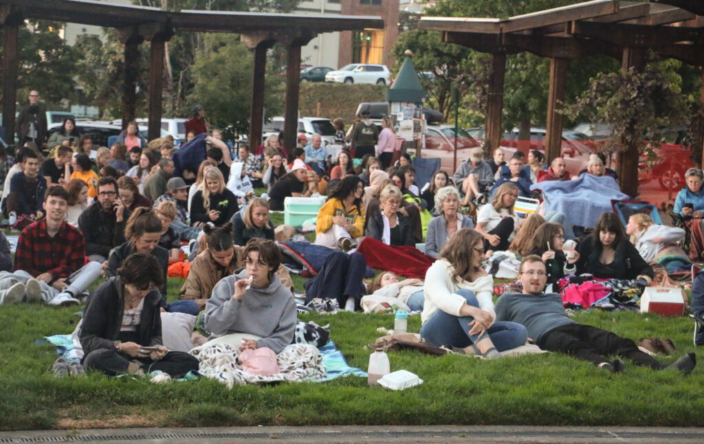 The Fairhaven Outdoor Cinema with crowds chatting as they wait on their picnic mats and some even brought blankets.