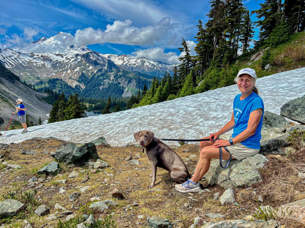 Chris Airoldi stops for a rest with Piper next to the Chain Lakes trail where other hikers are also resting with their dog.