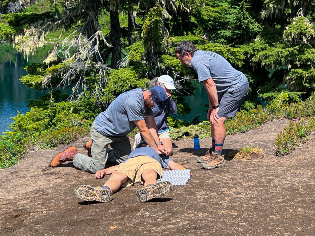 Bellingham EMT Alex Honn demonstrates how to perform CPR on Jim Kosa in a bright clearing.