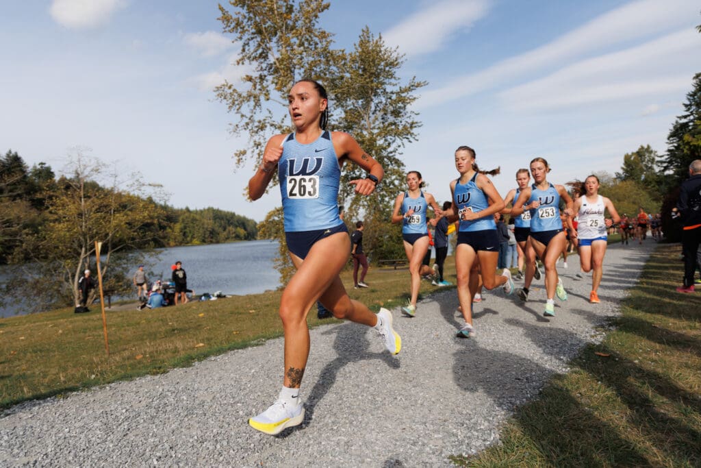 Western Washington University's Emma Smith runs ahead leaving a trail of runners consisting of her teammates and of other team members.