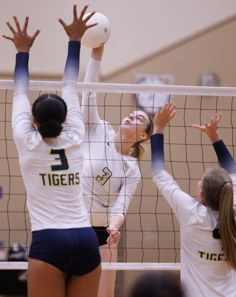 Meridian's Emry Claeys spikes the ball over the net as two Burlington-Edison defenders leap to block the ball.