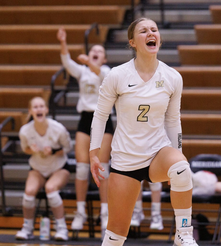 Meridian's Eden Bernardy celebrates a point as she yells along with her teammates who are cheering from the sideline.