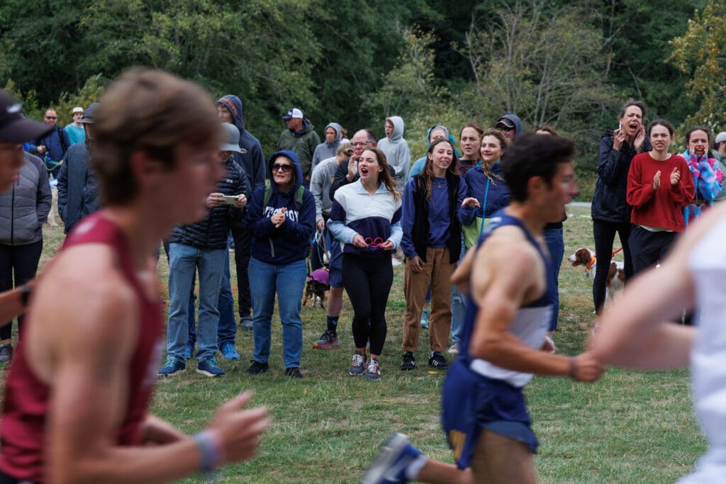 Spectators cheer on runners from the sidelines as the runners pass by.