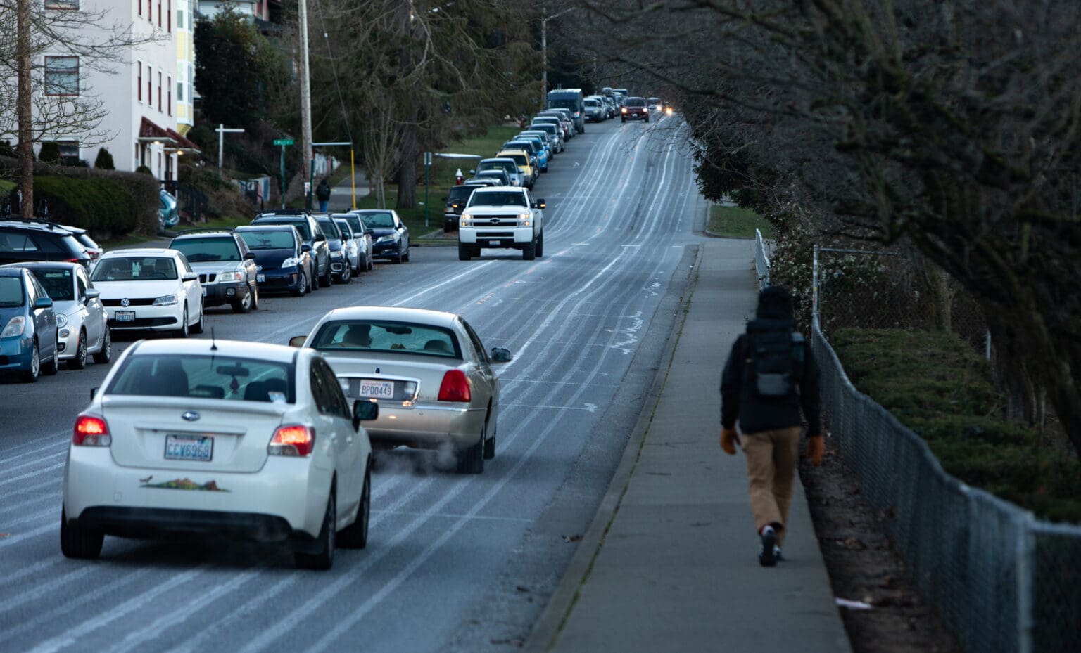 Lines of a deicing agent cover Garden Street as cars navigate their way down the road as a person walks on the sidewalk.