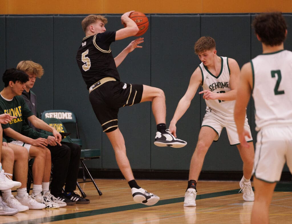 Meridian’s Jaeger Fyfe leaps to keep the ball in bounds as Sehome’s Austin McKay points to the line.