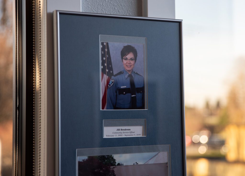 A photo commemorating Mayor Jill Boudreau's service hangs in her city hall office next to windows.