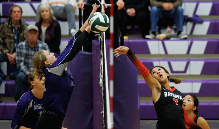 Bellingham’s Lilyauna Jude flips the ball over the net as defenders leap to try and block the ball.