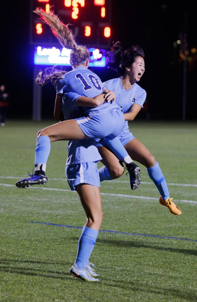 Western's Mie Cairns is hugged as teammates Claire Potter (10) and Morgan Manalili jump into her arms in celebration.