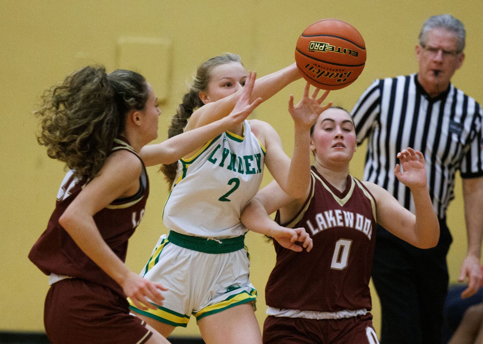 Lynden’s Kalanie Newcomb steals the ball from two Lakewood players as a referee watches closely.