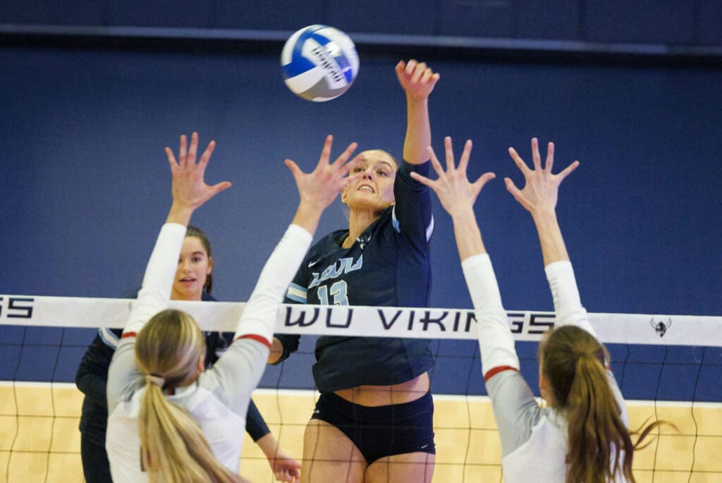 Western's Gabby Kepley spikes the ball as two defenders leap to try and block.