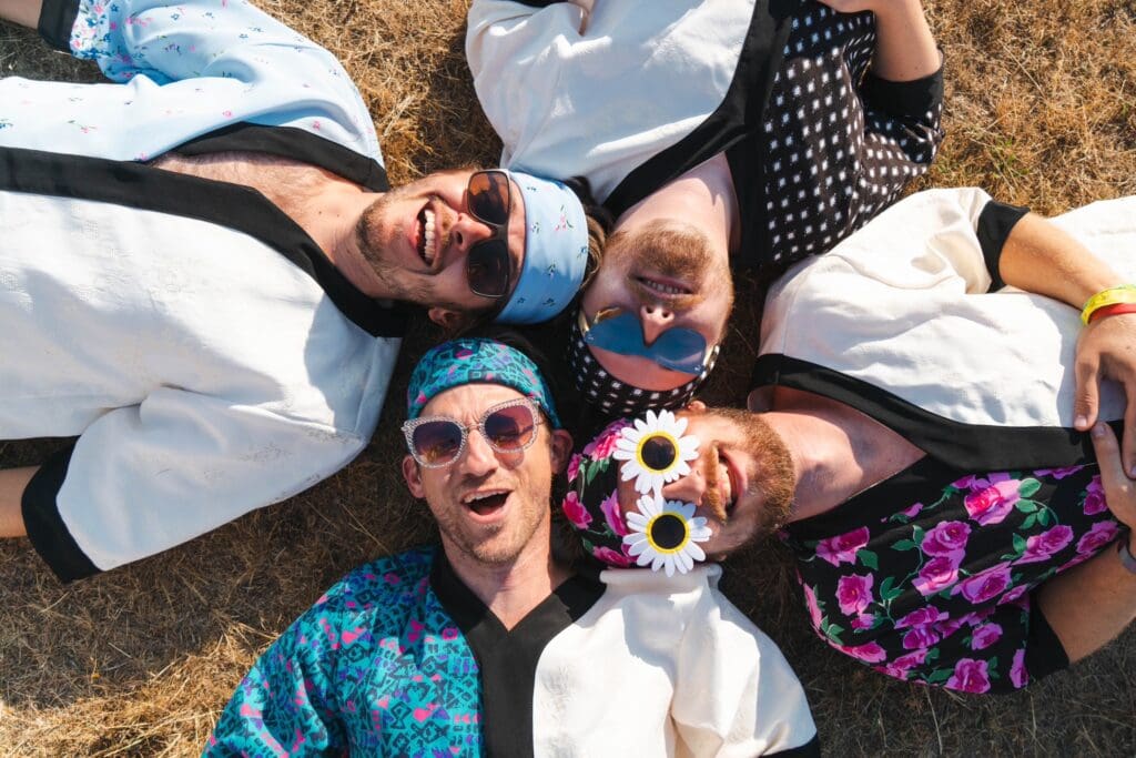 Whalien members laying on the ground wearing sunglasses and smiling at the camera.