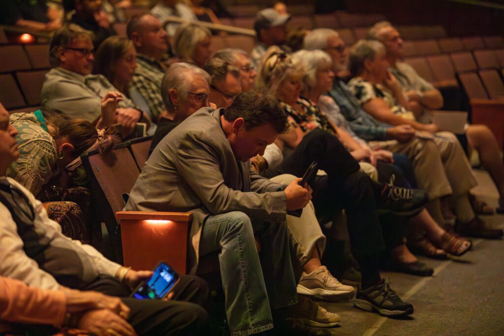 Michael Scholten, Mark's brother, bows his head at the end of the ceremony alongside other attendees sitting on the seats.