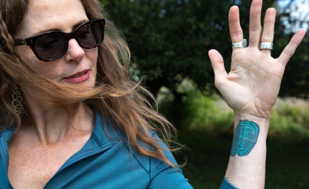 Kristen Winn shows a labyrinth tattoo on her arm that shows a light blue path lined with black ink.