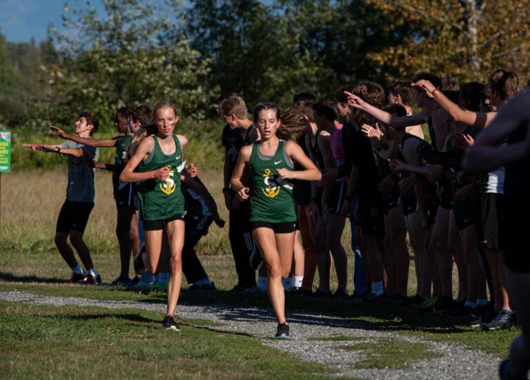 Sehome freshmen Lil Desler and Samantha Knipp pass a cheering section consisting of Sehome's boys team.