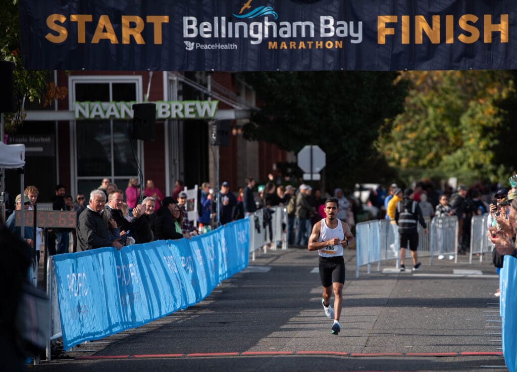 Adrian Cedillo running to the finish line as spectators watch from behind the barricades.