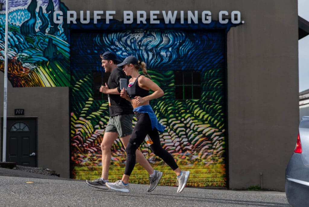 Whitaker Rapp and Claire Fuscoe runs past Gruff Brewing Co's wall art.