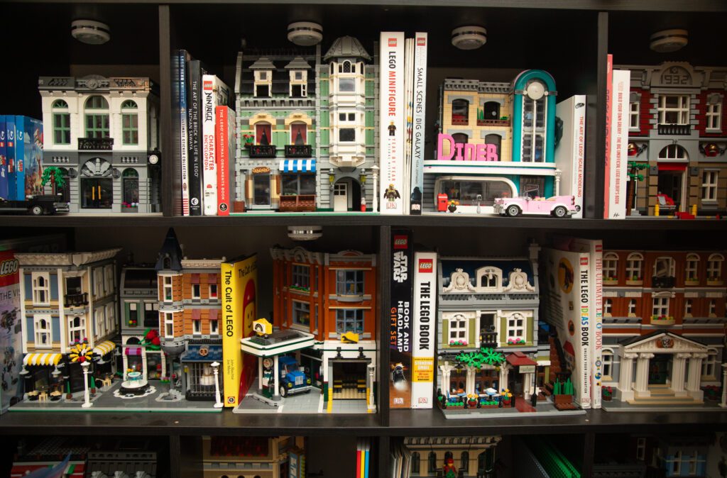 Lego Modular Houses and books line up a bookshelf alongside books focusing on Legos.