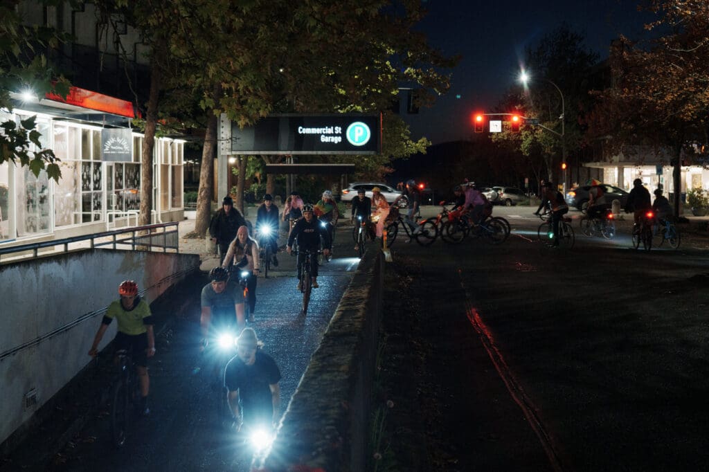 Bikers cycling down the Commercial Street Garage, shining bright lights as they speed by.