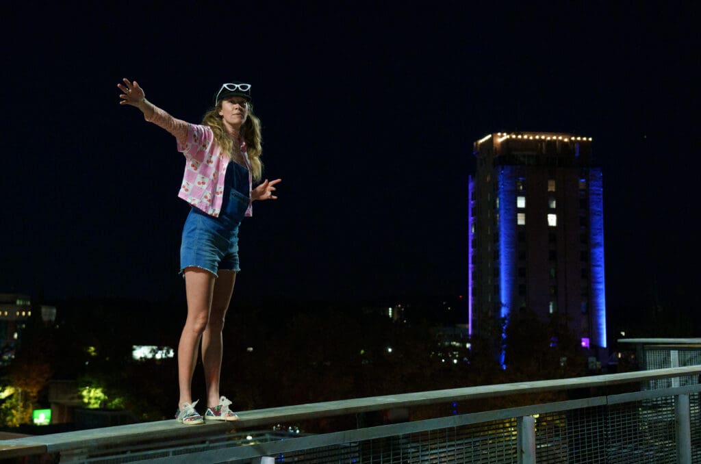 Leslie Grey directs the riders participating in the race by pointing to the correct direction as she stands on the railing.