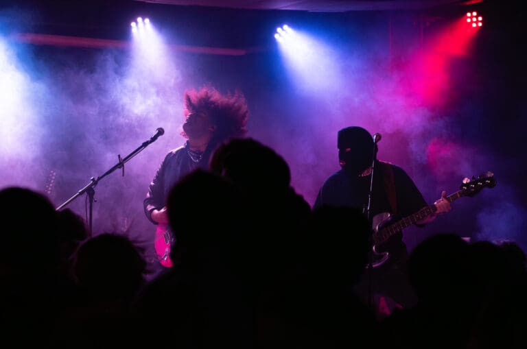 King Youngblood performing underneath a mix of blue, purple, and red spotlights.