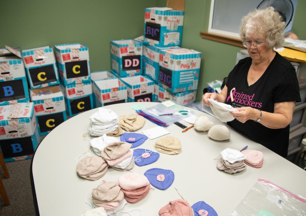 Char Malseed organizes donated, unstuffed knitted knockers by size by laying them out on the table.