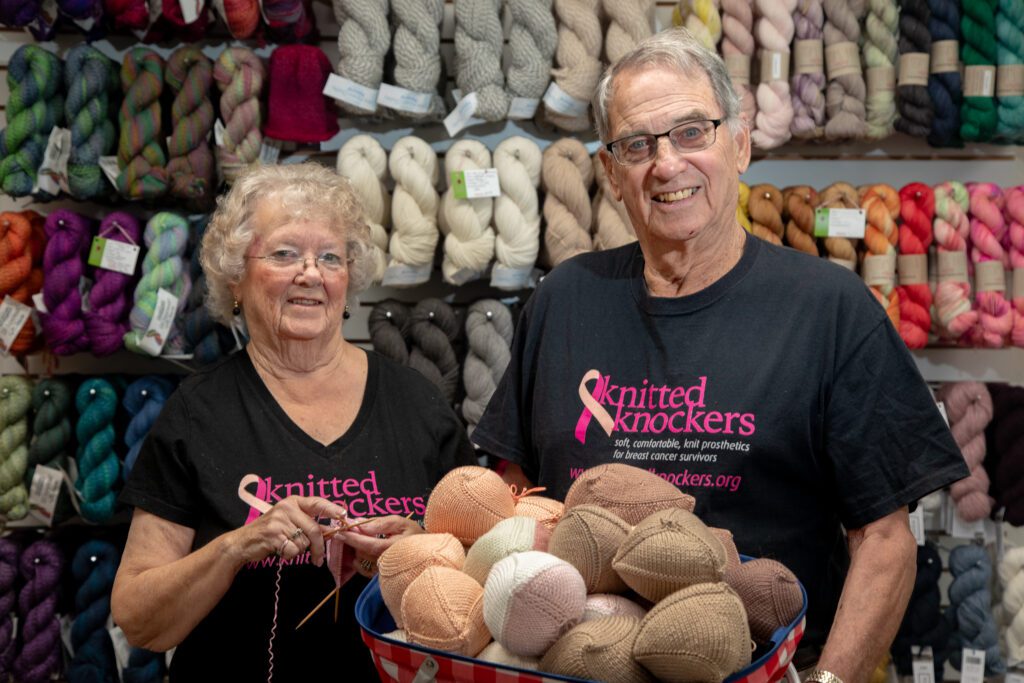 Char, left, and Ken Malseed hold knockers in front of rows of colorful yarn.