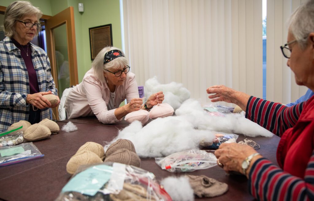 Volunteers, from left, Sue Hyndman, Christel Bronesma and Peggy Smith help stuff the knockers as one of them leans against the table next to stuffing.