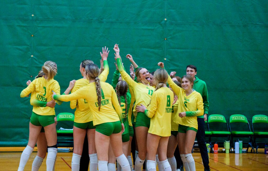 The Lions celebrate in a close huddle as they make faces and raise their arms.