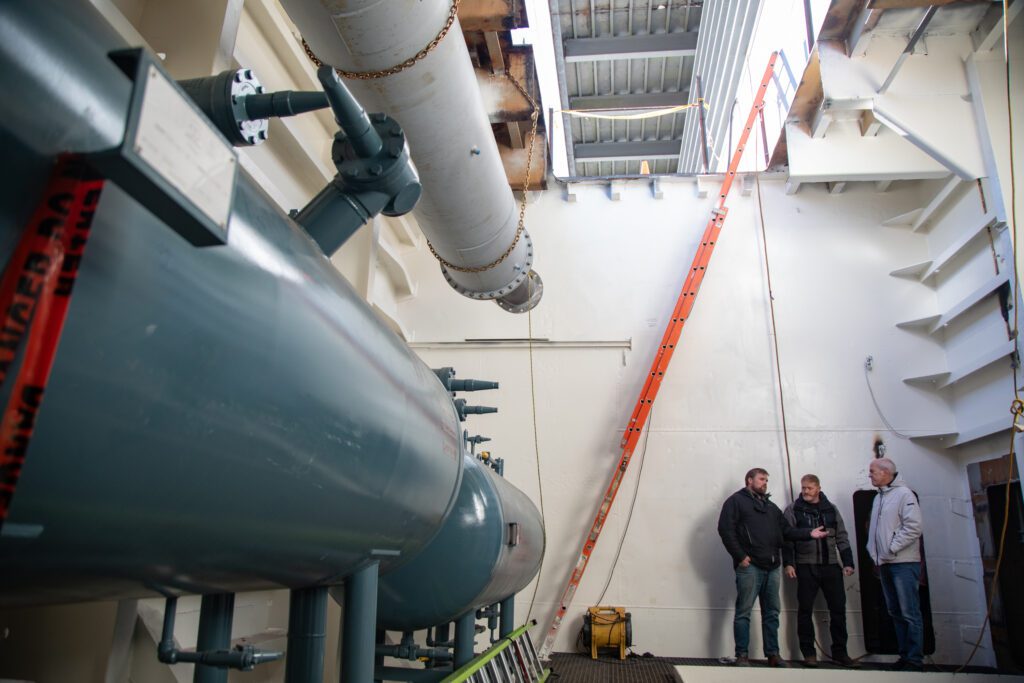 From left, Northline Seafoods CEO Benjamin Blakey, construction manager Justin Nichols and U.S. Rep. Rick Larsen talk next to large processing vessels meant to head to Alaska.