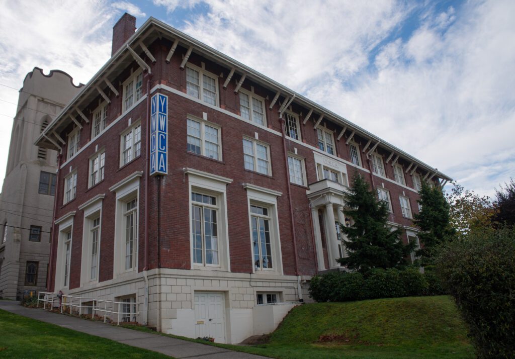 The YWCA building where the front entrance is covered by the trees and bushes that line up the path.