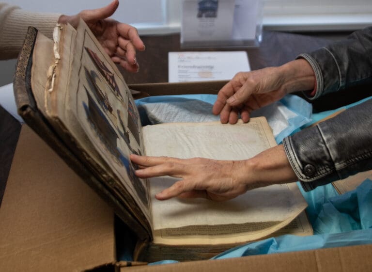 Sumas Museum President Liz Custer, left, and Secretary Helen Solem flip through an aged book full of writings and photos.