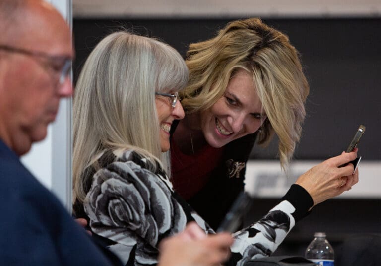 Ferndale School Board candidates Nancy Button, left, and Beth Perry talk and smile next to another candidate.