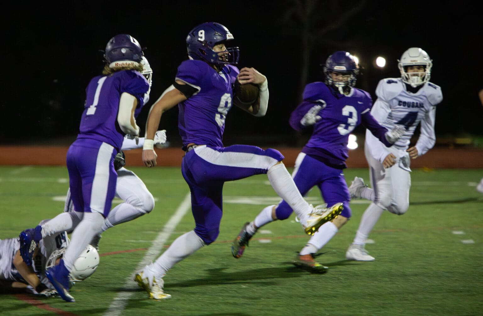 Nooksack Valley's Colton Lentz rushes with the ball as his teammates look out for him by preventing another player from reaching him.