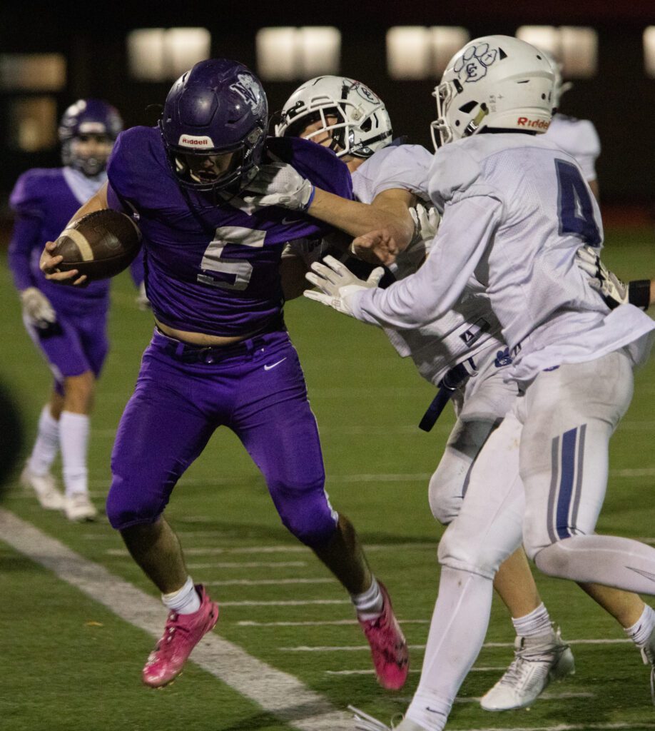 Nooksack Valley's Skyler Whittern with the ball in hand is tackled and shoved by two defenders.