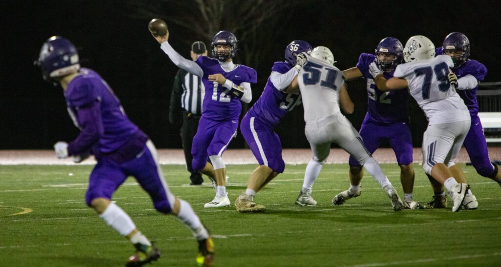 Nooksack Valley quarterback Joseph Brown looks to pass the ball as players scuffle with each other right next to him.