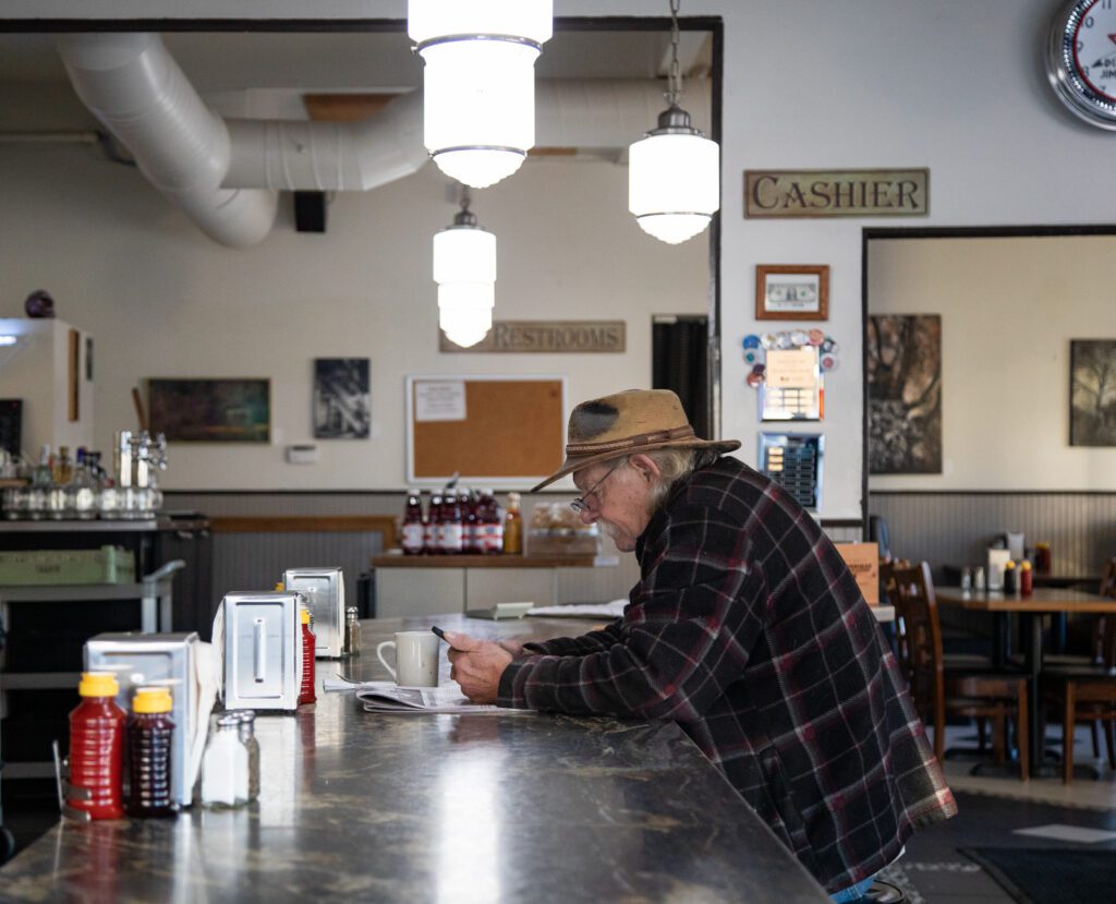 Mike Melim sits at the counter with his phone in his hands.