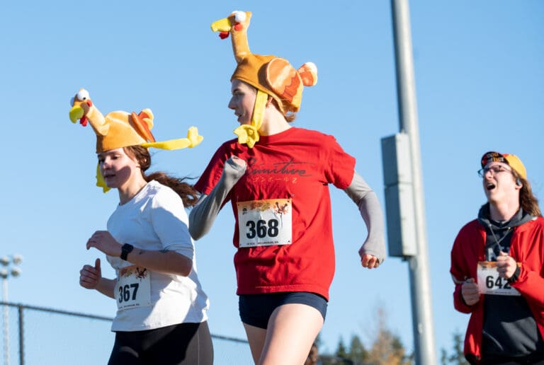 Serena Calkins, left, and Jewell Lower, middle, close in on the finish line wearing turkey-themed hats.