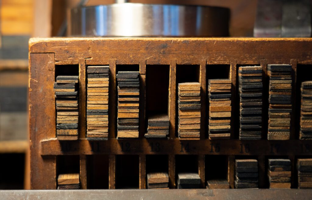 Wooden shims sorted into a wooden organizer with some slots with more stacks than others.