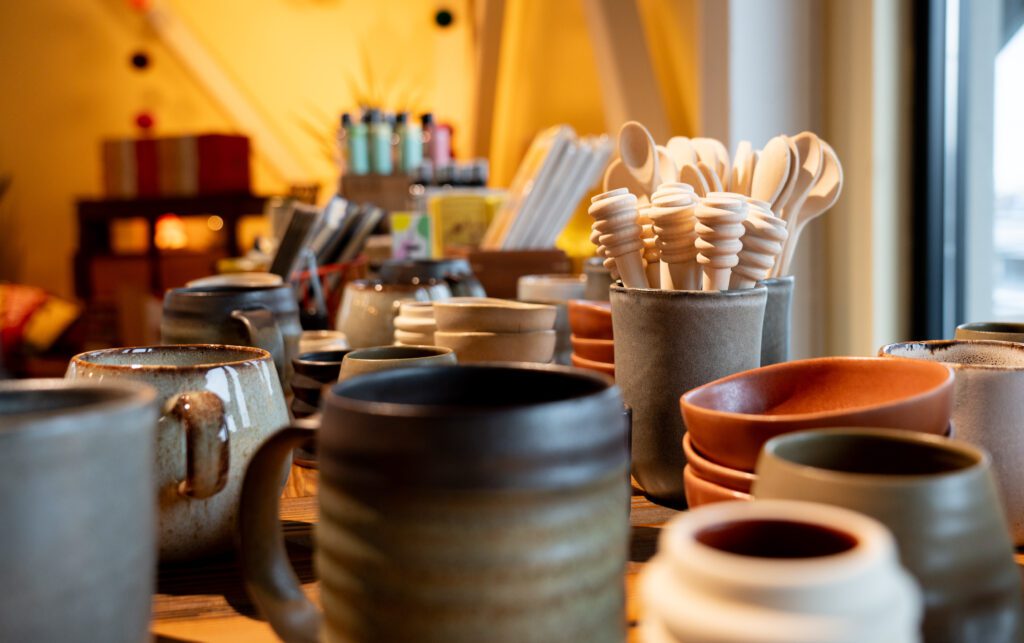 Ceramic mugs, cups, and other containers hold wooden spoons and other culinary items.