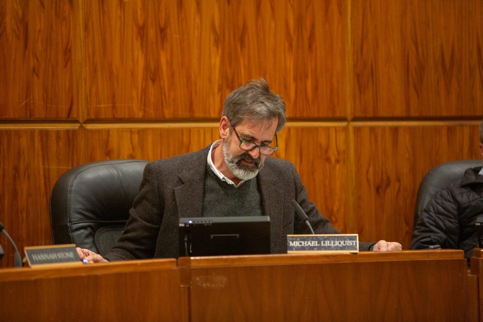 Council President Michael Lilliquist reads the resolution behind a wooden podium.