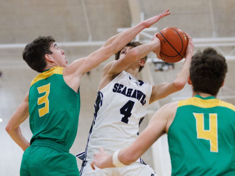 Anacortes' Davis Fogle gets ready to throw the ball as two defenders try to block the shot.