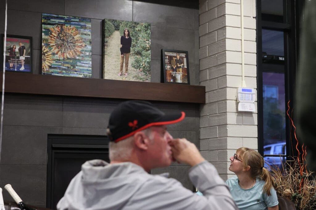 Marlena Geise looks up at a picture of Lucy Guerra as a man rubs his nose near her.