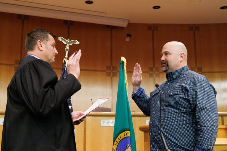 Judge Jonathan Rands swears in council member Ben Elenbaas next to the Washington State flag.