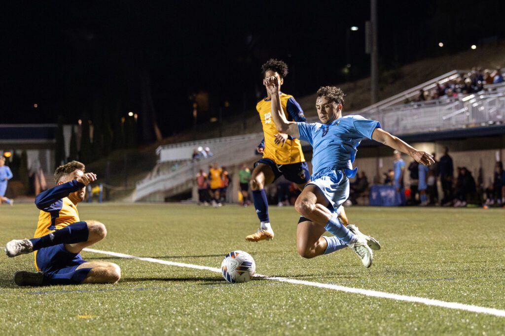 Western Washington University junior defender Jacob Sundberg dives for the ball as another player attempts to take control of the ball.