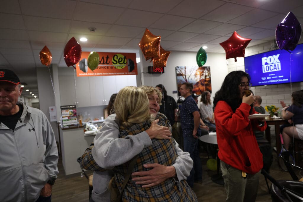 Amy Guerra gets a hug from a friend as others chat and eat cake.