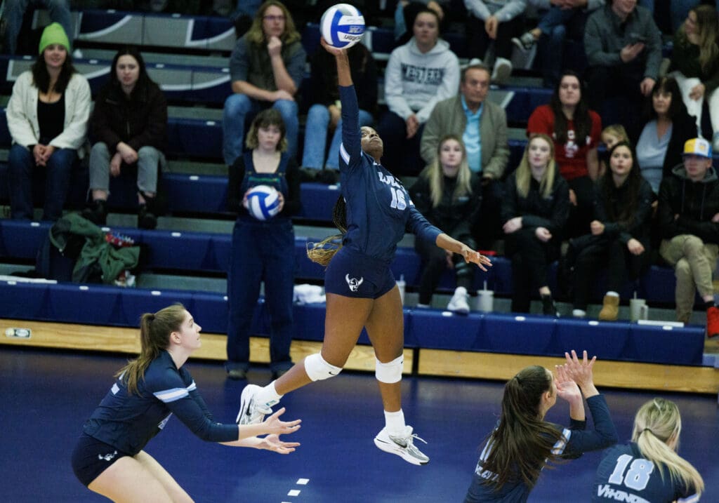 Western's Janelle Grant leaps and spikes the ball as spectators watch from the bleachers.